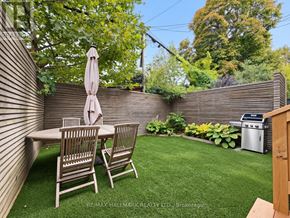 Toronto (Greenwood-Coxwell) apartment for rent - A backyard with a table and chairs and a grill.