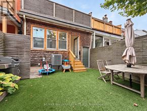 Toronto (Greenwood-Coxwell) apartment for rent - A backyard with a wooden deck, a table and chairs, and a play structure.