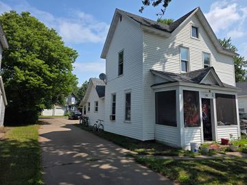 Eau Claire apartment for rent - A white house with a black roof and a bicycle parked in front.