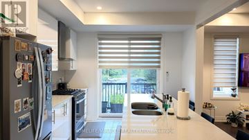 Whitby (Port Whitby) townhouse for rent - A kitchen with a refrigerator filled with magnets and a sink with a roll of paper towels on the counter.