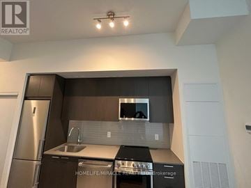 Newmarket (Central Newmarket) condo for rent - A modern kitchen with a stainless steel refrigerator and a built-in oven.