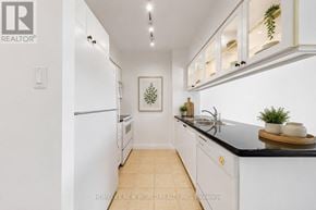 Toronto (Bay Street Corridor) condo for rent - A white kitchen with a black counter top and a fridge.