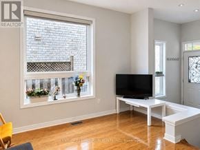 Markham (Berczy) apartment for rent - A living room with a television and a window with a view of a brick wall and flowers.