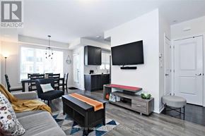 Vaughan (Maple) townhouse for rent - A living room with a grey couch, a black chair, a red coffee table, and a flat screen TV mounted on the wall.