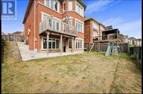 Brampton (Northwest Brampton) apartment for rent - A red brick house with a balcony and a green slide in the backyard.