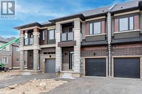 Brantford townhouse for rent - A large, multi-story residential building with a balcony and garage doors.