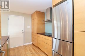 Ottawa triplex for rent - A kitchen with a stainless steel refrigerator, wooden cabinets, and a white door.
