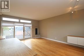 Ottawa triplex for rent - A spacious room with wooden floors and a large window with blinds.