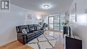 Toronto (Waterfront Communities) condo for rent - A living room with a black leather sofa and a wooden floor.