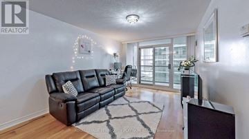 Toronto (Waterfront Communities) condo for rent - A living room with a black leather sofa and a wooden floor.
