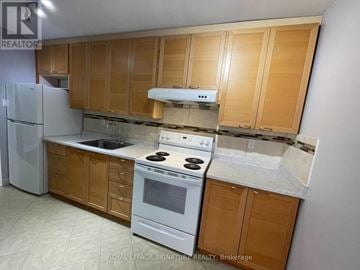 Toronto (Morningside) townhouse for rent - A kitchen with wooden cabinets and a white stove top oven.