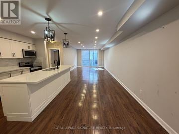 Toronto (Long Branch) townhouse for rent - A well-lit kitchen with white cabinets and a wooden floor.