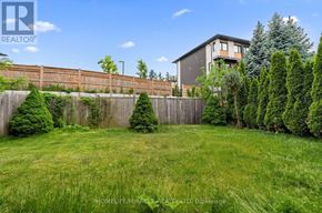 Guelph (Clairfields/Hanlon Business Park) apartment for rent - A backyard with a wooden fence and a house in the background.