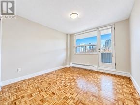 Toronto (University) condo for rent - A room with a wooden floor and a window overlooking a cityscape.