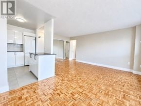 Toronto (University) condo for rent - A spacious living room with hardwood flooring and white walls.
