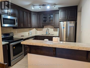 Mississauga (Cooksville) condo for rent - A kitchen with dark brown cabinets and stainless steel appliances.