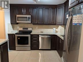 Mississauga (Cooksville) condo for rent - A kitchen with dark brown cabinets and stainless steel appliances.
