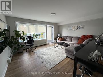 Ottawa multi-family for rent - A living room with a grey couch and a large window.