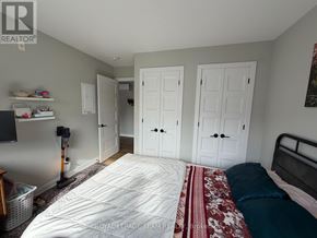 Ottawa multi-family for rent - A bedroom with a bed, two closets, and a vacuum cleaner.