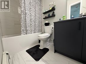 Ottawa multi-family for rent - A white toilet in a bathroom with a black mat in front of it.