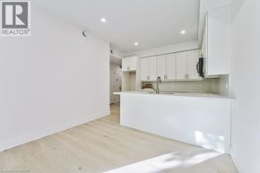 Kitchener apartment for rent - A white interior space with wooden flooring and a kitchen area.