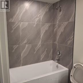 Toronto (Glenfield-Jane Heights) condo for rent - A white bathtub in a bathroom with grey tiles.