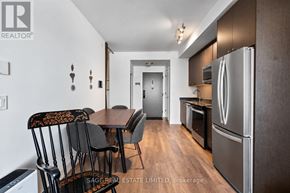 Oakville (Jm Joshua Meadows) condo for rent - A kitchen with a table and chairs in the foreground and a refrigerator in the background.