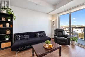 Oakville (Jm Joshua Meadows) condo for rent - A living room with a black couch, a wooden coffee table, and a large window overlooking the city.