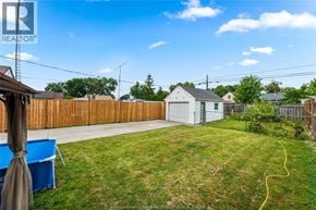 Windsor apartment for rent - A backyard with a white house, a blue tarp, and a wooden fence.