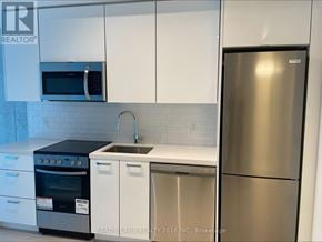 Toronto (Moss Park) condo for rent - A kitchen with a stainless steel refrigerator, microwave, oven, and sink.