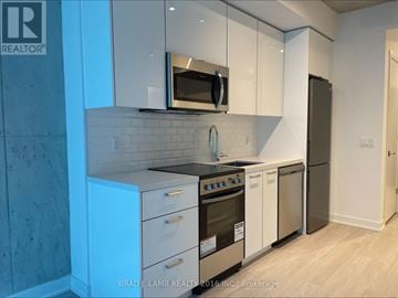 Toronto (Moss Park) condo for rent - A modern kitchen with white cabinets and a black countertop.