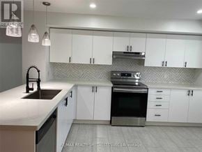 Mississauga (Churchill Meadows) townhouse for rent - A modern kitchen with white cabinets and a black stove top oven.