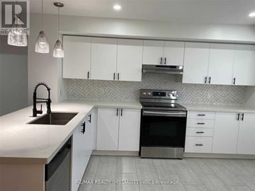 Mississauga (Churchill Meadows) townhouse for rent - A modern kitchen with white cabinets and a black stove top oven.