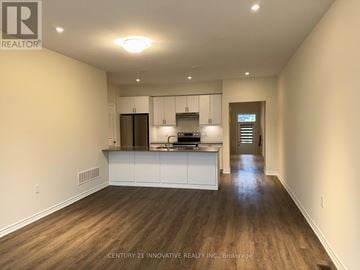 Kawartha Lakes (Bobcaygeon) townhouse for rent - A spacious kitchen with white cabinets and a wooden floor.