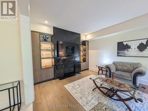 Niagara Falls (Brown) apartment for rent - A living room with a grey sofa and a wooden rocking chair.
