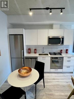 Toronto (Moss Park) condo for rent - A modern kitchen with white cabinets and a black chair.