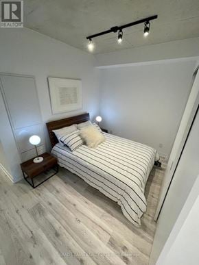Toronto (Moss Park) condo for rent - A bedroom with a bed, a nightstand with a lamp, and a picture frame on the wall.