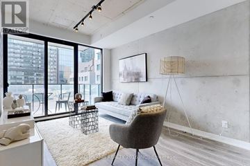 Toronto (Moss Park) condo for rent - A living room with a grey chair and a white couch.