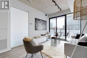 Toronto (Moss Park) condo for rent - A modern living room with a grey armchair and a white rug.
