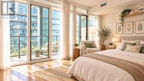 Toronto (Waterfront Communities) condo for rent - A well-lit bedroom with a large bed and a view of a cityscape through the windows.