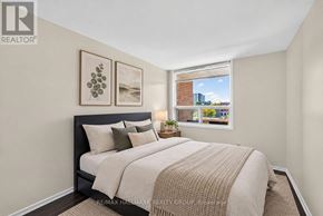 Ottawa condo for rent - A bedroom with a large bed and a window overlooking a cityscape.