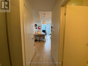 Toronto (Waterfront Communities) condo for rent - A hallway with a door on the right and a window in the distance.