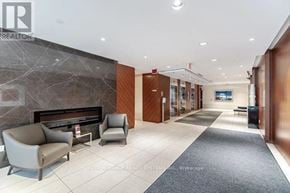 Toronto (Islington-City Centre West) condo for rent - A hallway with a stone wall and a fireplace with chairs on the side.