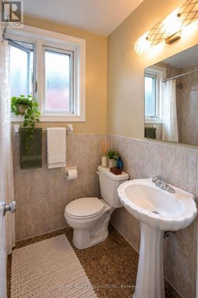 Toronto (Corso Italia-Davenport) triplex for rent - A bathroom with a toilet, sink, and mirror.