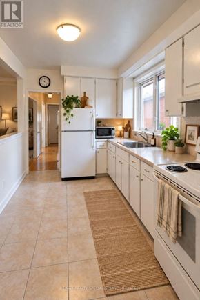 Toronto (Corso Italia-Davenport) triplex for rent - A white kitchen with a refrigerator, sink, and oven.