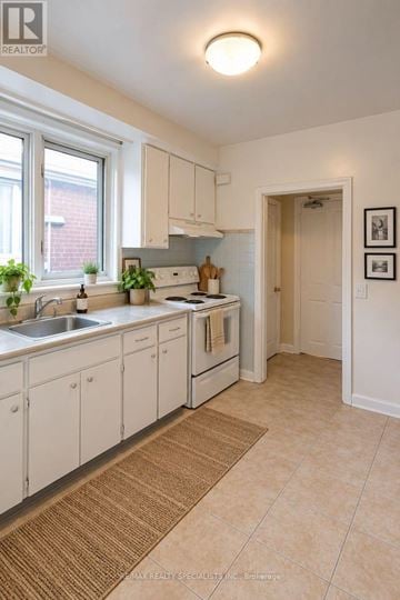 Toronto (Corso Italia-Davenport) triplex for rent - A kitchen with white cabinets and a window above the sink.