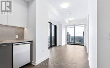 Kitchener condo for rent - A modern kitchen with white cabinets and a marble backsplash.