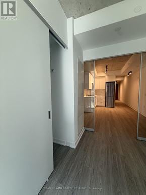 Toronto (Kensington-Chinatown) condo for rent - A hallway with a wooden floor and white walls.