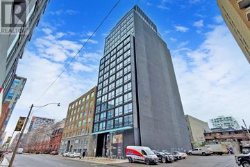 Toronto (Waterfront Communities) condo for rent - A tall building with a grey facade stands in the middle of a street.