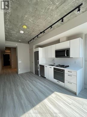 Toronto (Waterfront Communities) condo for rent - A modern kitchen with white cabinets and a grey floor.